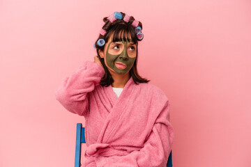 Young mixed race woman getting pretty in a house isolated on pink background touching back of head, thinking and making a choice.