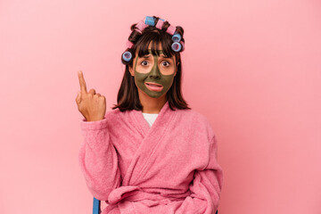 Young mixed race woman getting pretty in a house isolated on pink background showing a disappointment gesture with forefinger.