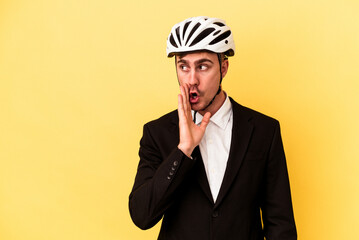 Young caucasian business man wearing a bike helmet isolated on yellow background is saying a secret hot braking news and looking aside