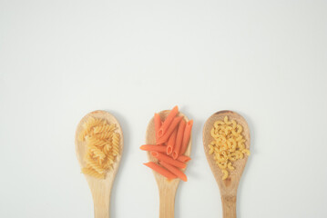 Dry pasta on wood spoon in a white background 