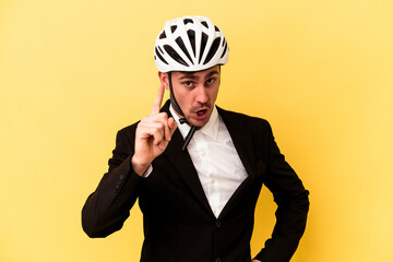 Young caucasian business man wearing a bike helmet isolated on yellow background having an idea, inspiration concept.
