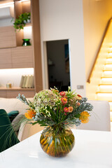A spherical glass vase with a bouquet of flowers on a white table in a modern designer interior. Soft selective focus, artistic noise.
