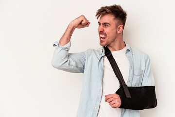 Young caucasian man with broken hand isolated on white background raising fist after a victory, winner concept.