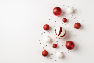 Top view photo of red and white christmas tree decorations balls and silver confetti on isolated white background with copyspace