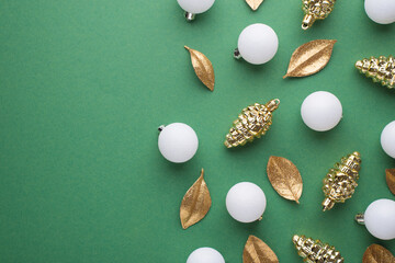 Top view photo of white christmas tree balls gold toys cones and golden leaves on isolated green background with copyspace
