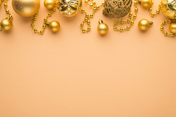 Top view photo of golden christmas tree balls and beard garland on isolated beige background with empty space