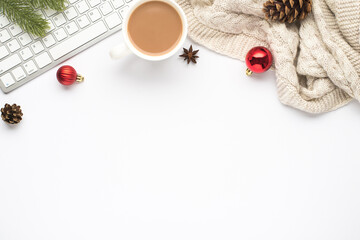 Naklejka premium Top view photo of keyboard cup of hot drinking red christmas tree balls pine twig cone anise and cozy sweater on isolated white background with copyspace