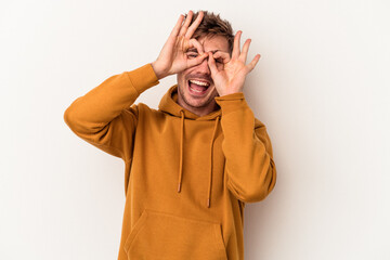 Young caucasian man isolated on white background showing okay sign over eyes