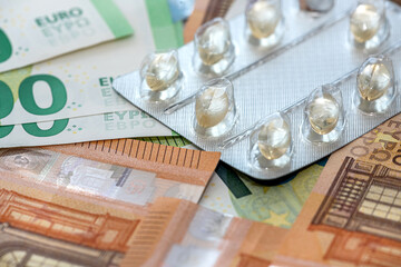 different medicine pills or capsules over euro bills