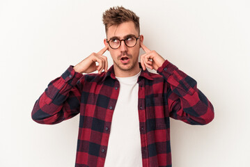 Young caucasian man isolated on white background covering ears with fingers, stressed and desperate by a loudly ambient.