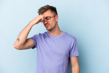 Young caucasian man isolated on blue background having a head ache, touching front of the face.