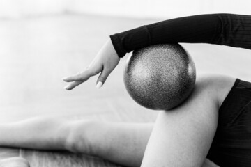 girl gymnast, is engaged with gymnastic objects in a light room, she is in a black leotard, performs exercises.