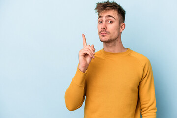 Fototapeta premium Young caucasian man isolated on blue background showing number one with finger.