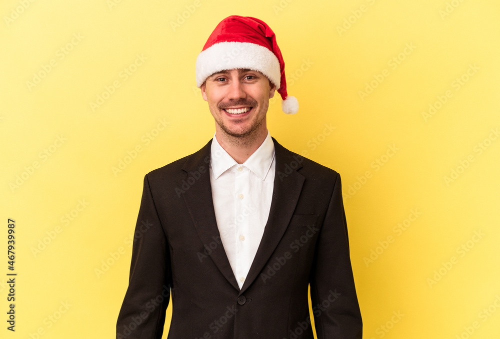 Wall mural young caucasian man celebrating new year wearing a christmas hat isolated on yellow background