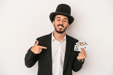 Young magician man holding a magic card isolated on white background person pointing by hand to a shirt copy space, proud and confident