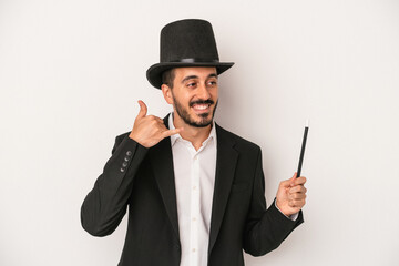 Young magician man holding wand isolated on white background showing a mobile phone call gesture with fingers.