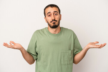 Young caucasian man isolated on white background doubting and shrugging shoulders in questioning...