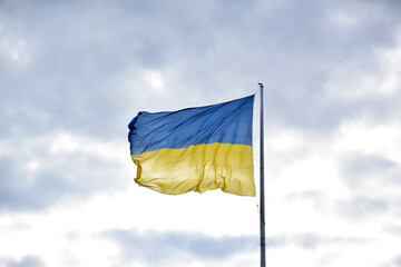 Large national flag of Ukraine flies in the blue sky. Big yellow blue Ukrainian state banner in the Kharkiv city.