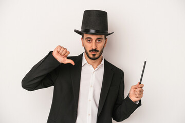 Young magician man holding wand isolated on white background showing a dislike gesture, thumbs down. Disagreement concept.