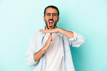 Young caucasian man isolated on blue background showing a timeout gesture.
