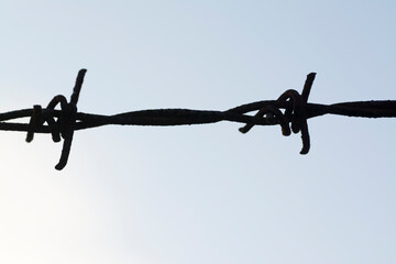 Barbed wire, counter light with sky.