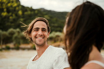 Caucasian male smiling at his girlfriend while walking by the sea