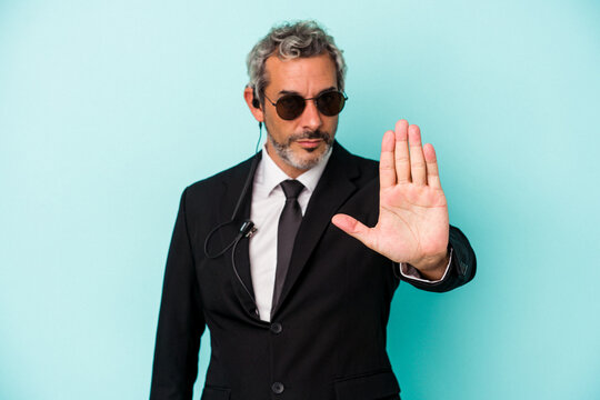 Middle age bodyguard caucasian man isolated on blue background  standing with outstretched hand showing stop sign, preventing you.