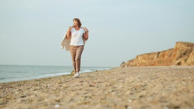 Positive mature woman walking on the beach