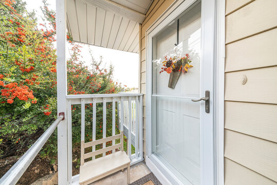 Entrance of a house with glass storm door over the white door with hanging flower decoration