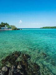 Scenic view of Koh Kham Island sand bar and crystal clear turquoise water with rock foreground. Near Koh Mak Island, Trat Province, Thailand.