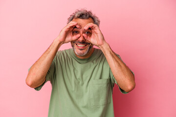 Middle age caucasian man isolated on pink background  showing okay sign over eyes