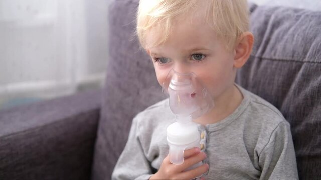 Close up portrait of cute little blond boy spraying respiratory diseases at home
