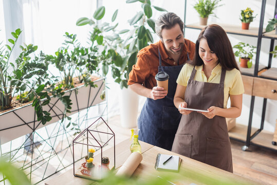 Cheerful Florists With Paper Cup Using Digital Tablet In Flower Shop