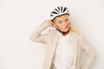 Young business Russian woman holding bike helmet isolated on white background touching back of head, thinking and making a choice.