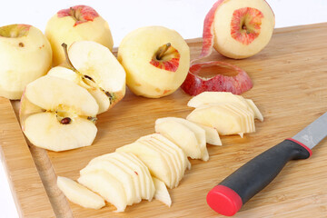 peeled and cut apples on a wooden board with a knife 