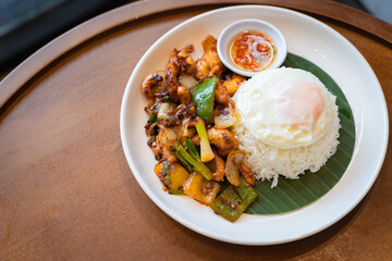 Thai food, Stir-fried chicken with cashew nuts top on rice on a wooden table. Consists of chicken, Thai Cashewnuts, sweet pepper, spring onion, with gravy oyster sauce juicy.
