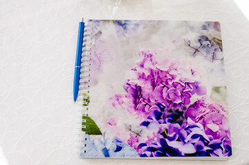 Fountain pen on notebook, pocketbook with bouquet of violet flowers. copy space.