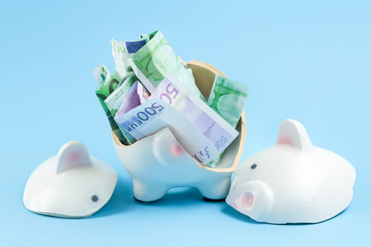 broken piggy bank in the form of a pig on a blue background. Concept - Crisis, decrease in incomes of the population during a pandemic, expenses from savings. Horizontal photo.