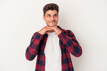 Young caucasian man isolated on white background keeps hands under chin, is looking happily aside.