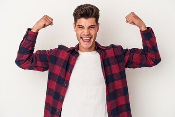 Young caucasian man isolated on white background showing strength gesture with arms, symbol of feminine power