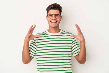 Fototapeta premium Young caucasian man isolated on white background holding something with palms, offering to camera.