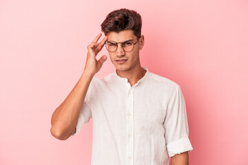 Young caucasian man isolated on pink background pointing temple with finger, thinking, focused on a task.