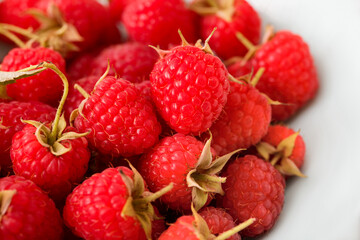 Ripe and sweet varietal raspberries on a white background. Large red berries
