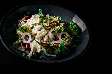 Mediterranean red beans salad with mix of lettuce leaves and onion on black plate