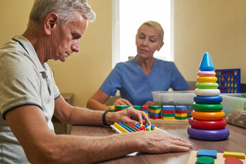 Mature patient using physiotherapy equipment for brain exercise in clinic