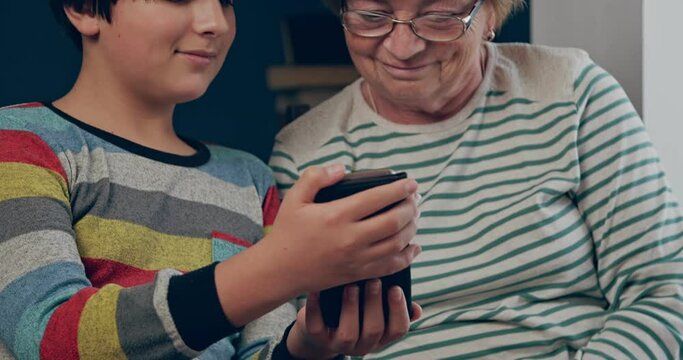 The grandson is showing his grandmother something in his smartphone. Communication through gadgets