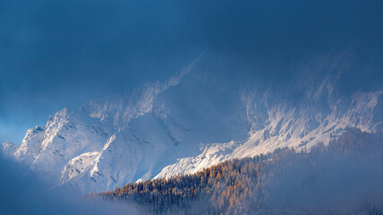 a window in the fog with view of the sunny and fresh snow capped alps at a november day