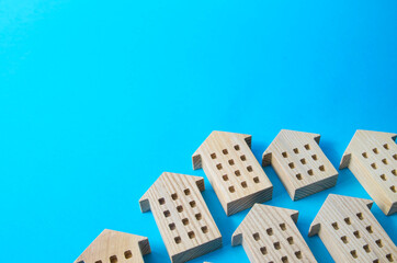 Figures of houses on a blue background with place for text. Investing in real estate and construction industry. Mortgage. Buying a home for young families. Social support in purchase of housing.