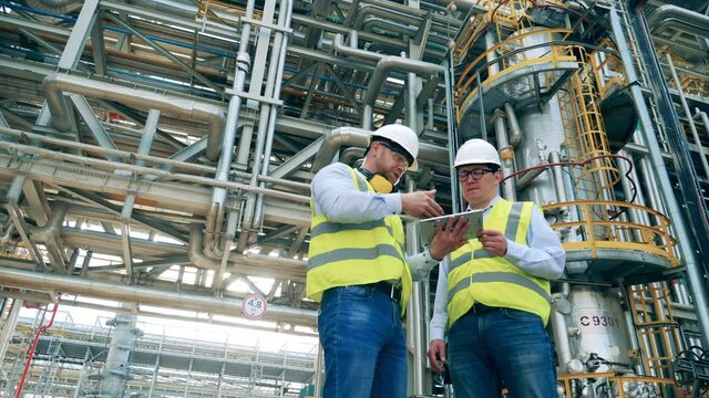 Oil refinery pipelines with work partners talking near them