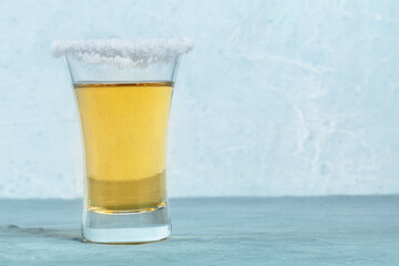 Gold tequila shot with a salted rim, a Mexican drink, side view with copy space